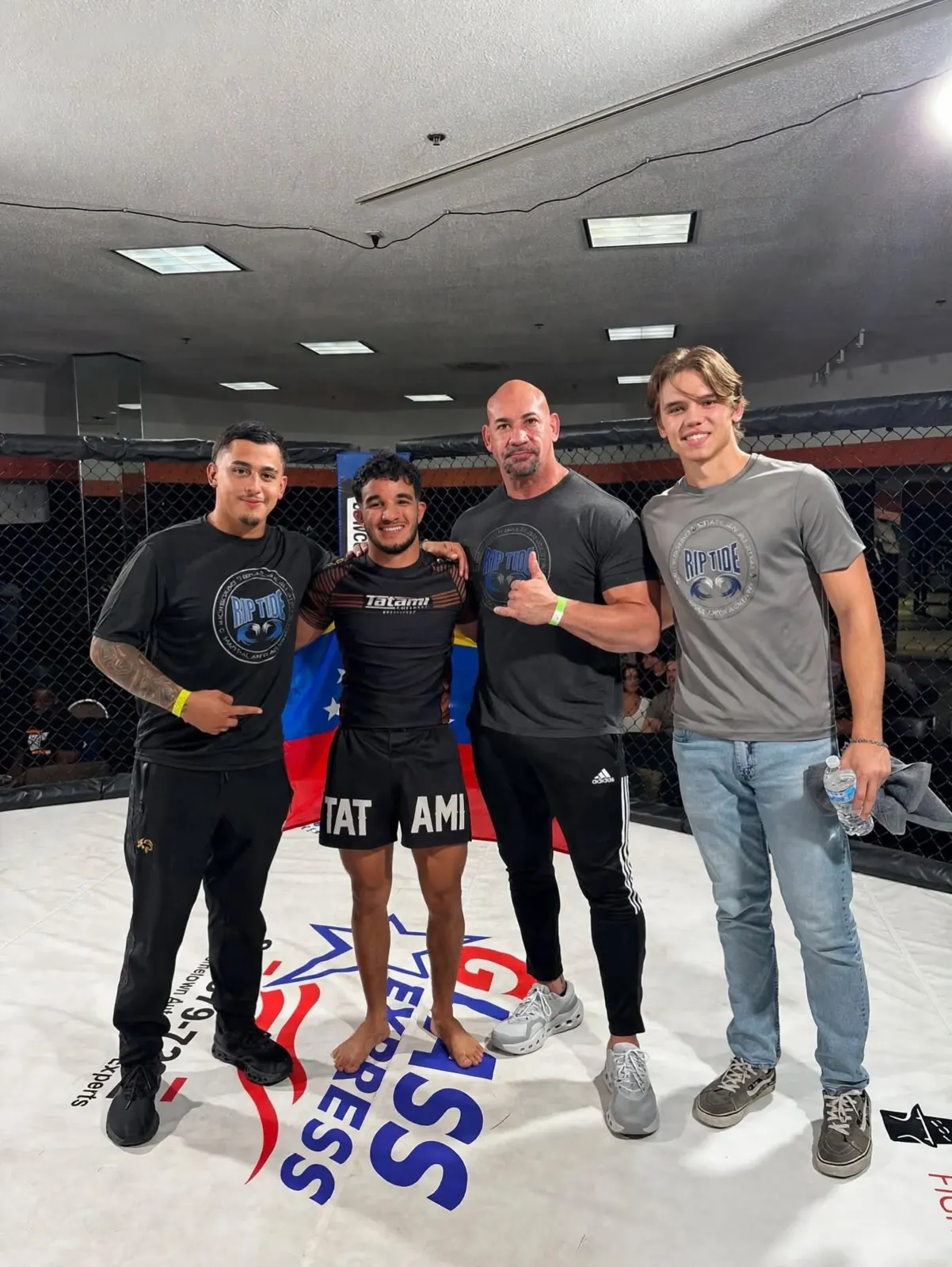 Riptide teammates and supporters together beside a cage at a martial arts event