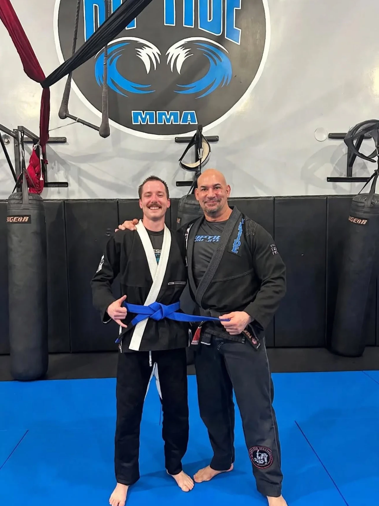 A Riptide student and coach sharing a blue-belt promotion moment